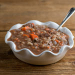 Beef barley soup in a bowl with a spoon.