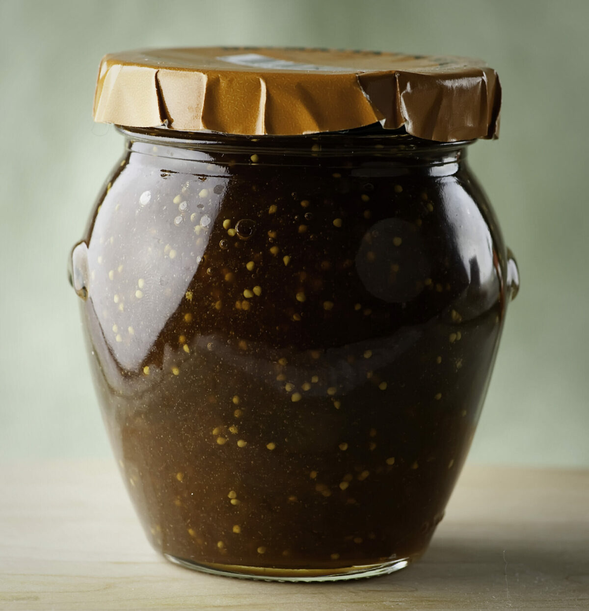 Fig Jam in a glass jar on a board.