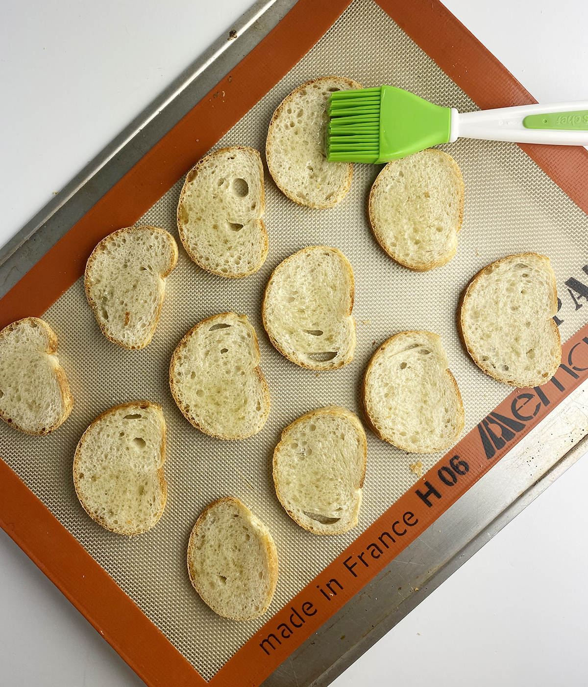 Brushing french bread slices with olive oil.