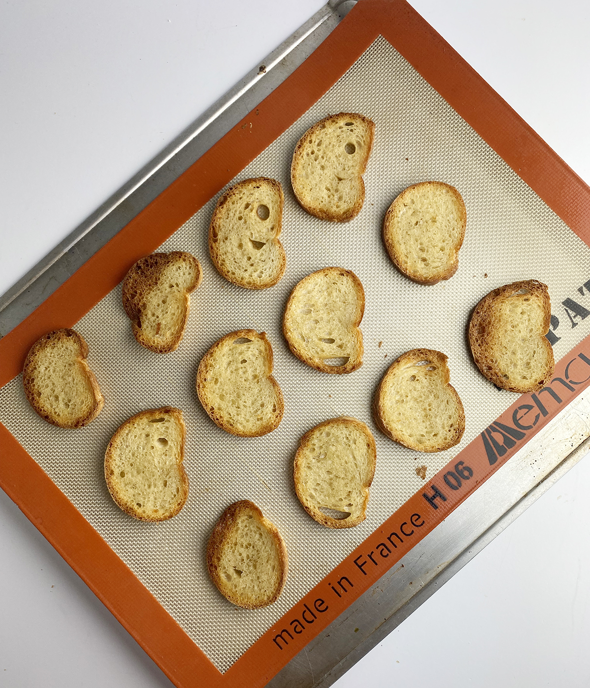 Toasted french bread slices on a baking pan.