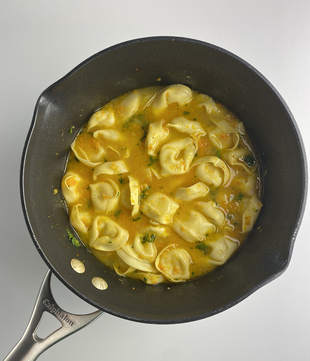 Chicken tortellini soup in a pot.