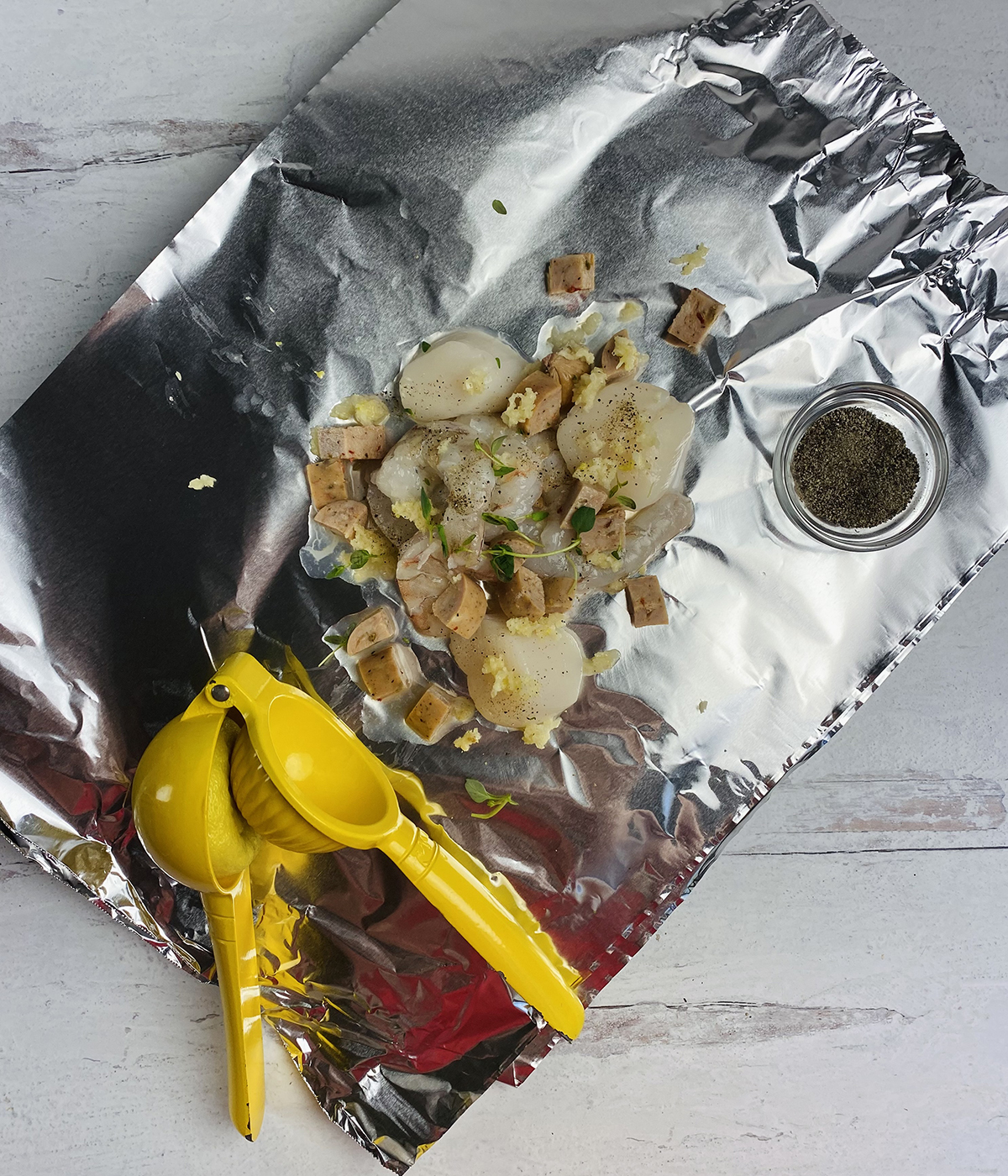 Seafood with herbs and lemon juice on a piece of foil.