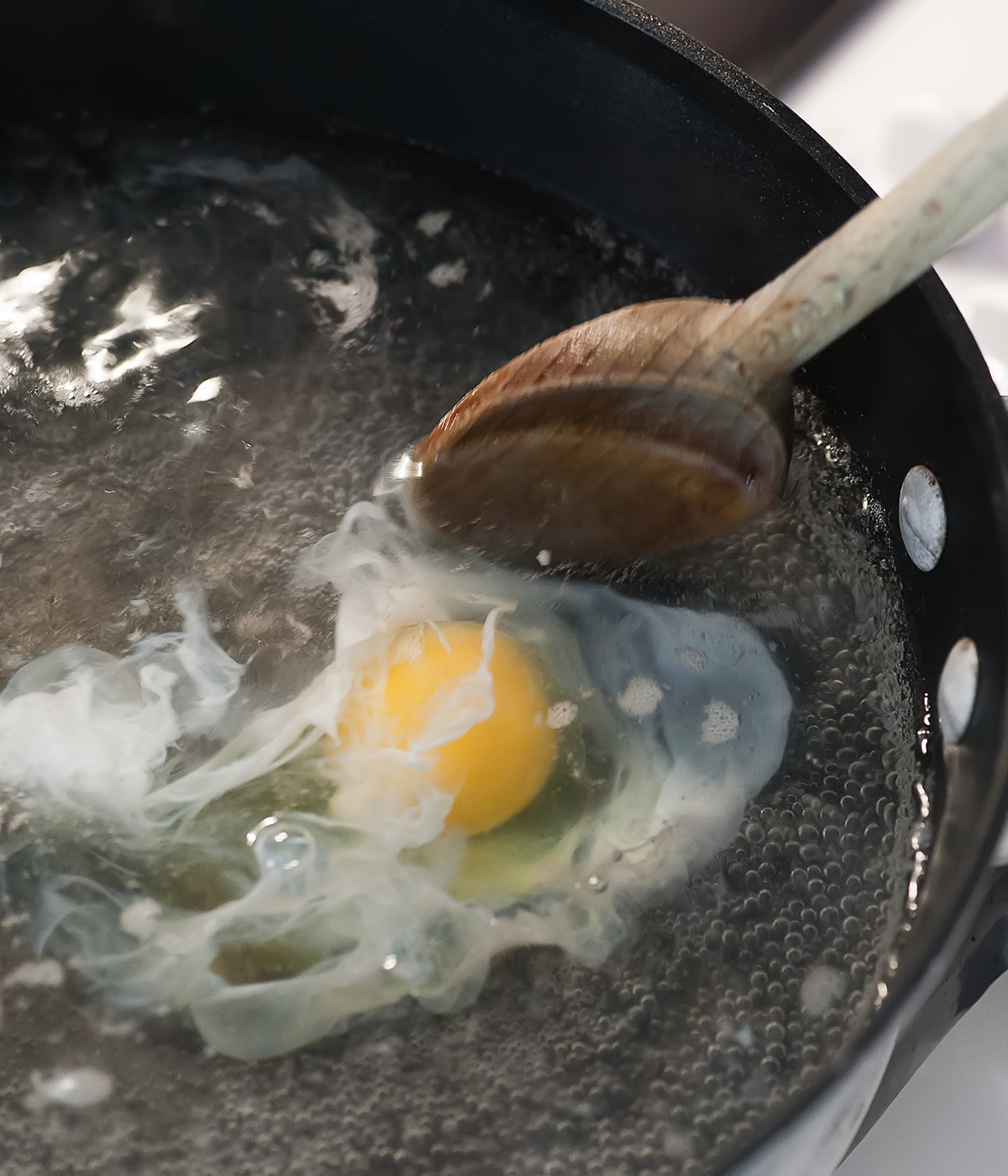 Egg being poached in a skillet.