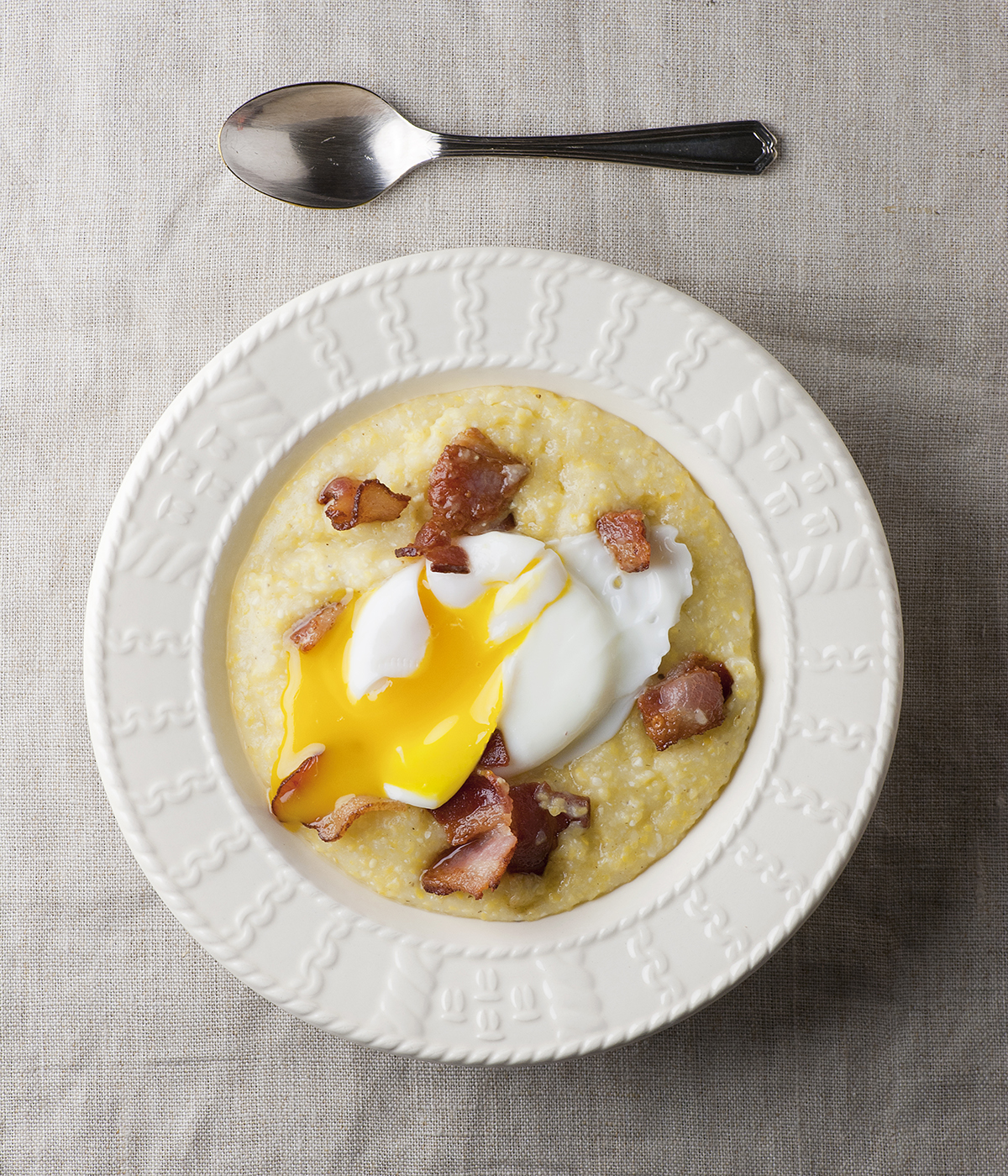 Poached egg in a bowl of creamy bacon grits.