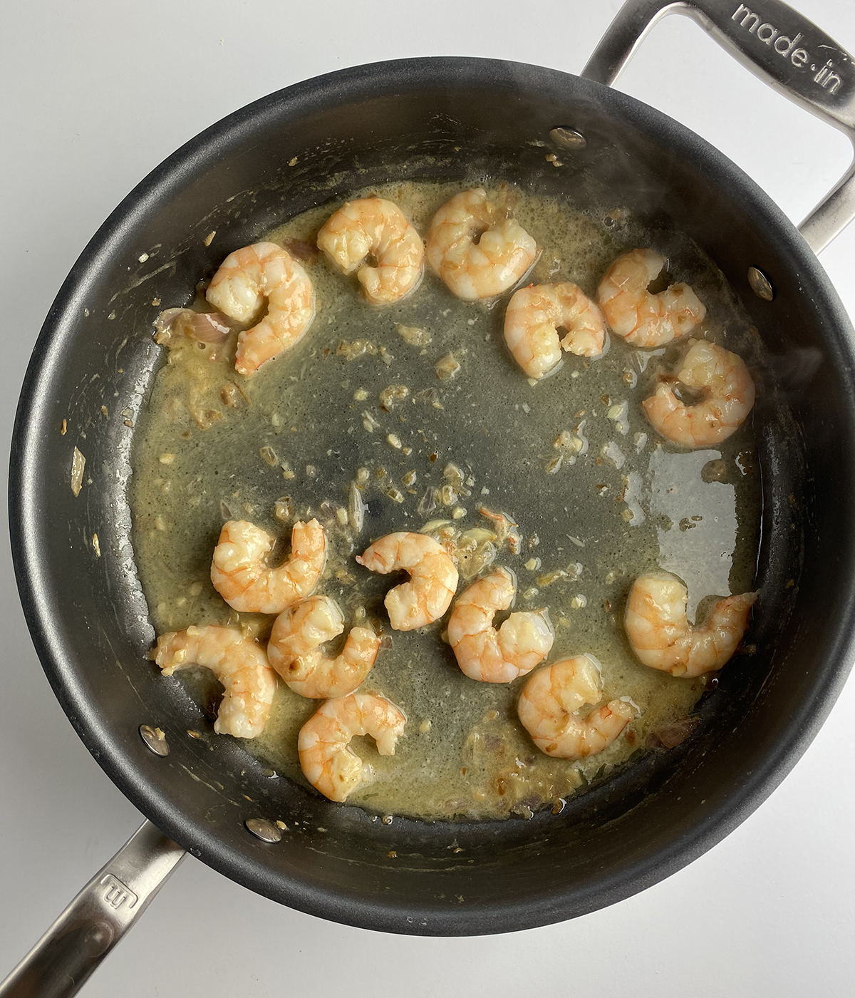 Shrimp cooking in scampi sauce.