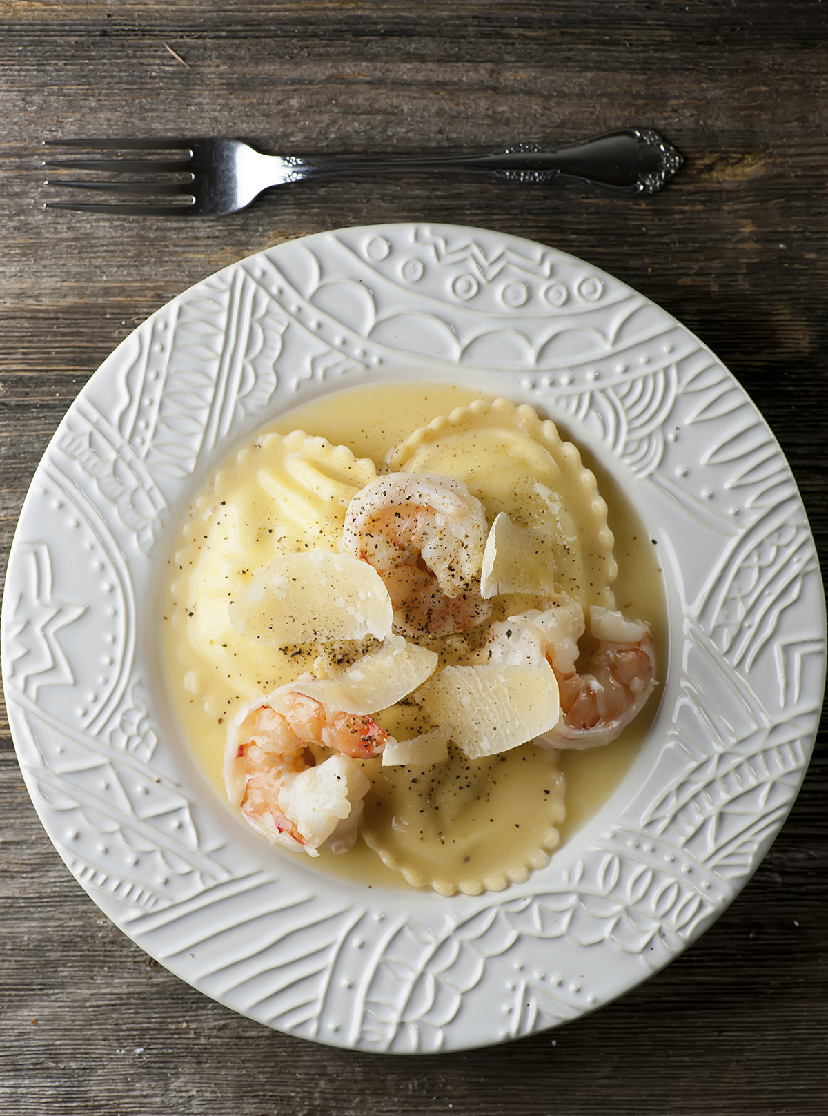 Shrimp scampi ravioli on a plate with a fork.