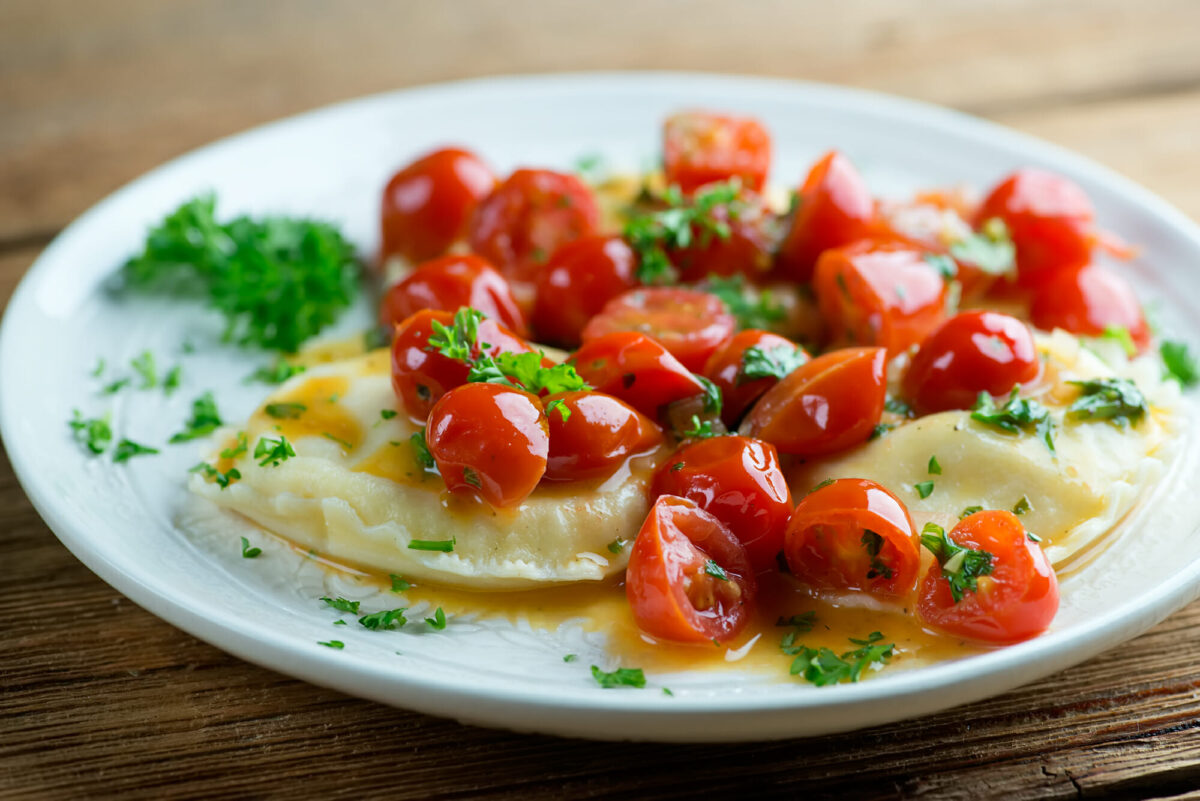 Ravioli with white wine tomato sauce on a plate.